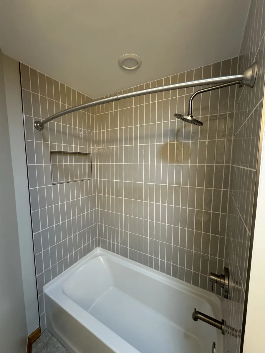 Columbus guest bathroom remodel featuring gray vertical subway tile, recessed shower niche, new bathtub, and brushed nickel fixtures.